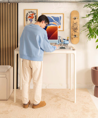 person using a compact standing desk in a home workspace
