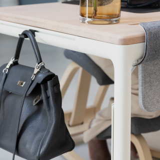 A purse hangs on a Lode haging hook attached to the side of a Tenon Desk