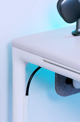 Close-up of a tenon mini desk with a lamp and cable, on a light blue gradient background