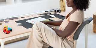 A woman sits at a Tenon desk from Beflo