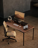 Modern office desk with computer setup and chair in a room with gray walls.