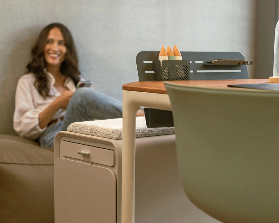 Woman sitting on a couch next to a beflo desk with a chair in a home office setting.