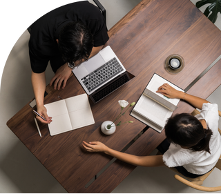 An overhead view of two people working at the Tenon desk