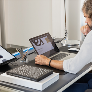 A man sots and uses a laptop at a Tenon desk