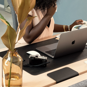 A woman reads a magazine while seated at a Tenon desk