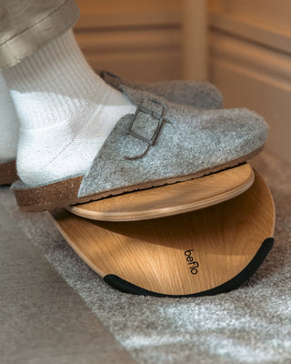 Person wearing gray loafers on a wooden balance board with 'beflo' branding.