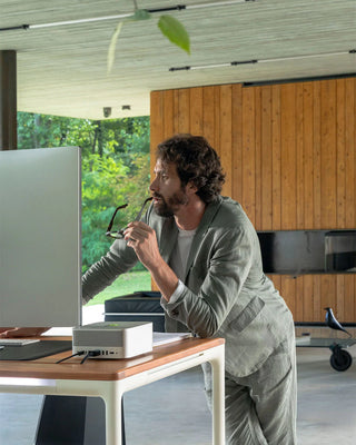 Man sitting at a beflo Tenon desk in a modern office space, looking at a computer screen.